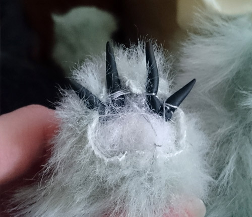 Sewing bear claws onto bear paws